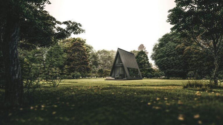 Exterior of rural creative cottage in shape of triangle located on grassy lawn in abundant forest